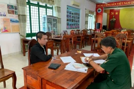 Cán bộ Đồn Biên phòng cửa khẩu quốc tế Mộc Bài lập biên bản bắt người đang bị truy nã đối với Lê Quang Dần (trái). (Ảnh: TTXVN phát)