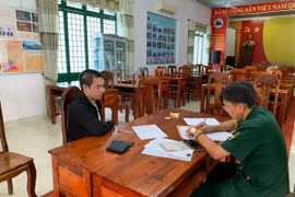 Cán bộ Đồn Biên phòng cửa khẩu quốc tế Mộc Bài lập biên bản bắt người đang bị truy nã đối với Lê Quang Dần (trái). (Ảnh: TTXVN phát)