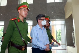 Lực lượng chức năng dẫn giải bị cáo Nguyễn Thanh Long (cựu Bộ trưởng Bộ Y tế) đến phiên tòa. (Ảnh: Phạm Kiên/TTXVN)