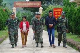 Lực lượng biên phòng áp giải 2 đối tượng mua bán người. (Ảnh: Quang Duy/TTXVN)