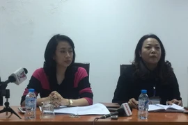 Bà Nguyễn Thị Thanh Hằng, Chánh văn phòng Ủy ban Nhân dân quận Long Biên (áo đỏ đen), thông tin về việc tạm dừng cải tạo nghĩa trang Bãi Xém. (Ảnh: Văn Thắng/Vietnam+)