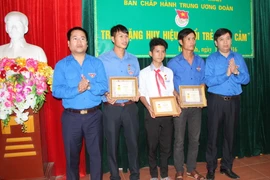 Trao tặng Huy hiệu 'Tuổi trẻ dũng cảm' cho 3 đoàn viên thanh niên là Võ Phong (34 tuổi), Võ Huân (28 tuổi) và em Đặng Quốc Vinh (13 tuổi) đã dũng cảm cứu người trong mưa lũ. (Ảnh: Hoàng Ngà/TTXVN)