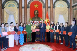 Chủ tịch nước Trần Đại Quang tặng quà cho các cá nhân điển hình tiên tiến, quần chúng và thân nhân gia đình tiêu biểu có nhiều đóng góp trong phong trào phòng, chống ma túy tại buổi gặp mặt. (Ảnh: Nhan Sáng/TTXVN) 