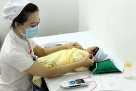 Nhân viên y tế sàng lọc khiếm thính cho sơ sinh tại Trung tâm Sàng lọc-chẩn đoán trước sinh và sơ sinh. (Ảnh: Dương Ngọc/TTXVN)