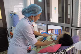 Bác sỹ thăm khám cho mẹ con sản phụ mới sinh. (Ảnh: TTXVN)