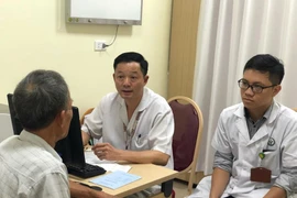 Phó giáo sư Đỗ Trường Thành khám cho một bệnh nhân. (Ảnh: PV/Vietnam+)
