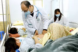 Phó giáo sư Đỗ Duy Cường khám cho một thai phụ mắc bệnh sởi. (Ảnh: PV/Vietnam+)