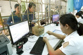 Làm thủ tục cho bệnh nhân khám bệnh bảo hiểm y tế. (Ảnh: Dương Ngọc/TTXVN)