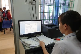 Nhân viên y tế làm thủ tục khám bệnh cho người dân. (Ảnh: T.G/Vietnam+)