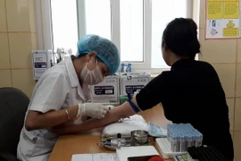 Nhân viên y tế lẫy máu xét nghiệm cho bệnh nhân tại Bệnh viện K. (Ảnh: PV/Vietnam+)