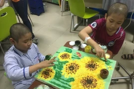 Bệnh nhân ung thư vẽ tranh để trưng bày tại ngày hội. (Ảnh: PV/Vietnam+)