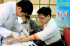 Cán bộ y tế lấy máu xét nghiệm cho người bệnh. (Ảnh: TTXVN/Vietnam+)