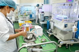 Nhân viên y tế thực hiện việc chăm sóc cho trẻ sơ sinh. (Ảnh: Dương Ngọc/TTXVN)