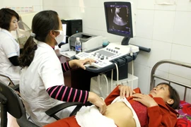 Nhân viên y tế siêu âm sàng lọc dị tật thai nhi cho thai phụ. (Ảnh: Dương Ngọc/TTXVN)