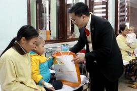 Đại diện Quỹ Hỗ trợ bệnh nhân ung thư Ngày mai tươi sáng tặng quà cho bệnh nhi ung thư. (Ảnh: TTXVN)