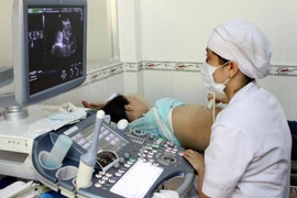 Nhân viên y tế siêu âm sàng lọc dị tật bẩm sinh cho thai phụ. (Ảnh: Dương Ngọc/TTXVN)