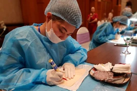 Thí sinh tham gia cuộc thi đang thực hiện xăm môi trên mẫu bài thi. (Ảnh: PV/Vietnam+)