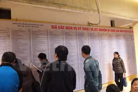 Người dân quan sát bảng giá viện phí mới tại một bệnh viện. (Ảnh: PV/Vietnam+)