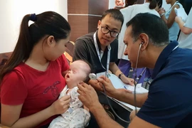 Bác sỹ của tổ chức Facing the world thăm khám cho các em nhỏ dị tật. (Ảnh: TG/Vietnam+)
