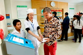 Nhân viên y tế hướng dẫn người dân làm thủ tục khám chữa bệnh. (Ảnh: Dương Ngọc/TTXVN)