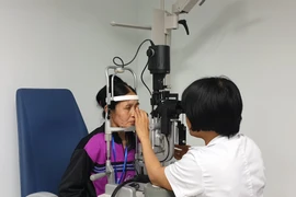 Bác sỹ khám mắt cho người dân. (Ảnh: T.G/Vietnam+)