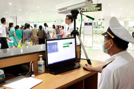 Kiểm tra nhiệt độ hành khách bằng máy đo thân nhiệt tia hồng ngoại. (Ảnh: TTXVN/Vietnam+)