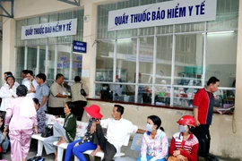 Người dân chờ xếp hàng mua thuốc. (Ảnh: TTXVN/Vietnam+)