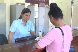 Cán bộ y tế hướng dẫn người dân làm thủ tục tham gia bảo hiểm y tế. (Ảnh: Nguyễn Cường/TTXVN)