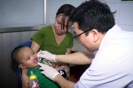 Bác sỹ Bệnh viện Hữu nghị Việt Nam Cu Ba khám cho trẻ bị sứt môi. (Ảnh: PV/Vietnam+)
