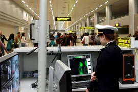  Nhân viên Trung tâm Kiểm dịch Y tế quốc tế kiểm tra thân nhiệt và kê tờ khai y tế cho hành khách. (Ảnh: Dương Ngọc/TTXVN)