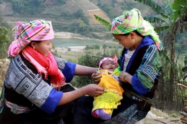 Cô đỡ thôn bản huyện Mù Cang Chải (bên trái) hướng dẫn bà mẹ chăm sóc trẻ sơ sinh. (Ảnh: TTXVN/Vietnam+)