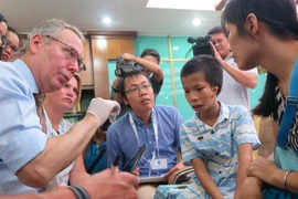 Chuyên gia thăm khám cho trường hợp bệnh nhân bị dị tật hàm mặt. (Ảnh: PV/Vietnam+)