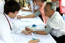 Nhân viên y tế đo huyết áp cho người dân. (Ảnh: TTXVN/Vietnam+)