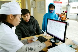 Nhân viên y tế làm thủ tục khám chữa bệnh cho người dân. (Ảnh: TTXVN/Vietnam+)