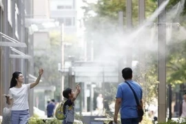 Người dân giải nhiệt tại các vòi phun nước ở Tokyo. (Nguồn: Kyodo/TTXVN)