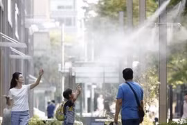 Người dân giải nhiệt tại các vòi phun nước ở Tokyo. (Nguồn: Kyodo/TTXVN)