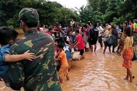 Người dân sơ tán khỏi các khu vực ngập lụt sau sự cố vỡ đập thủy điện Sapien. (Ảnh: Reuters/TTXVN)