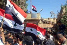 Người dân Syria giương cao quốc kỳ sau khi quân đội giành quyền kiểm soát tỉnh Daraa từ lực lượng nổi dậy ngày 12/7 vừa qua. (Ảnh: AFP/TTXVN)