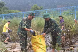Bộ đội biên phòng cửa khẩu Hoành Mô cùng nhân dân dọn vệ sinh môi trường trên sông biên giới Đồng Mô. (Ảnh: Văn Đức/TTXVN)