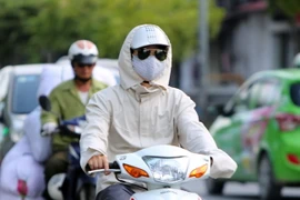 Người dân ra đường với trang phục kín mít để tránh nắng. (Ảnh: Thành Đạt/TTXVN)