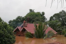 Người dân chờ cứu hộ tại vùng ngập lụt do sự cố vỡ đập thủy điện Xe Pian-Xe Namnoy ở Attapeu ngày 24/7. (Ảnh: THX/TTXVN)