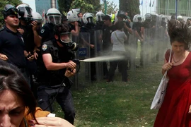 Cô gái mặc váy đỏ bị cảnh sát xịt hơi cay vào mặt. (Nguồn: Reuters)