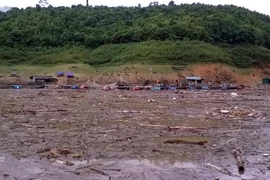 Do mưa lớn, nước dâng cao, bùn đất và rác từ các nơi đổ về nên việc tìm kiếm thi thể em Hoàng Thị Nhàn gặp nhiều khó khăn. (Nguồn: TTXVN)