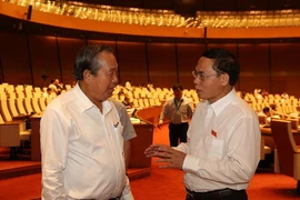 Phó Thủ tướng thường trực Chính phủ Trương Hòa Bình (bên trái) trao đổi với đại biểu Quốc hội bên lề phiên họp. (Ảnh: Dương Giang/TTXVN)