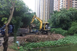 Ủy ban Nhân dân phường Trung Văn tổ chức phương tiện để xúc những phần vật liệu đổ trộm tại hồ Ngòi. (Ảnh: Nguyễn Thắng/TTXVN)