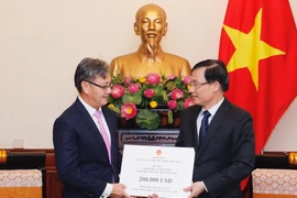 Thứ trưởng Bộ Ngoại giao Lê Hoài Trung (bên phải) trao tượng trưng số tiền Chính phủ Việt Nam hỗ trợ Chính phủ, nhân dân Lào khắc phục hậu quả sự cố vỡ đập thủy điện ở tỉnh Attapeu. (Ảnh: Lâm Khánh/TTXVN)