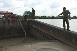 Lực lượng chức năng bắt giữ tàu công suất lớn đang chứa cát được bơm hút trái phép trên sông Đồng Nai. (Ảnh: Sỹ Tuyên/TTXVN)