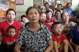 Bà Nguyễn Thị Hoa (mẹ tiền đạo Công Phượng) chăm chú theo dõi và cổ vũ cho đội tuyển Olympic Việt Nam. (Ảnh: Tá Chuyên/TTXVN)