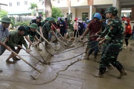 Lực lượng công an, bộ đội, giáo viên và phụ huynh học sinh tổng dọn vệ sinh tại trường Tiểu học thị trấn Mường Xén sau khi nước lũ rút. (Ảnh: Tá Chuyên/TTXVN)