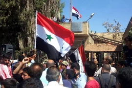 Người dân Syria giương cao quốc kỳ sau khi quân đội giành quyền kiểm soát tỉnh Daraa từ lực lượng nổi dậy ngày 12/7. (Ảnh: AFP/TTXVN)